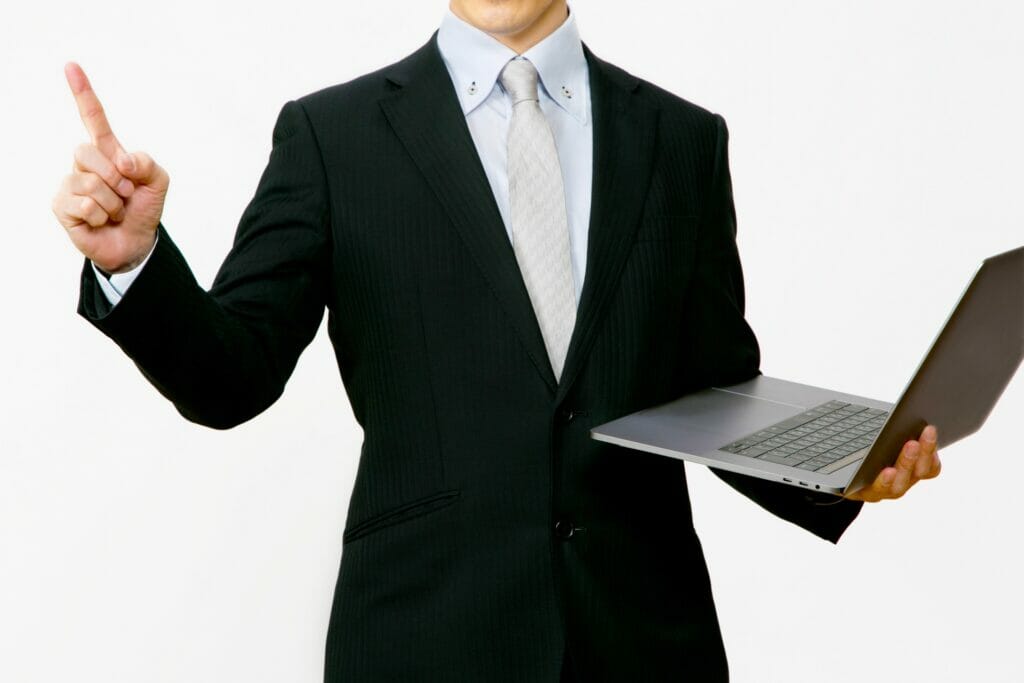 ノートパソコン、人差し指を立てるビジネスマン